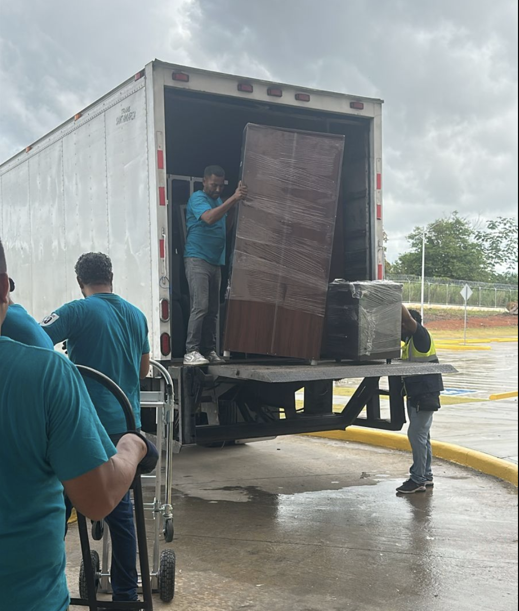 Equipo descargando mobiliario corporativo protegido desde un camión